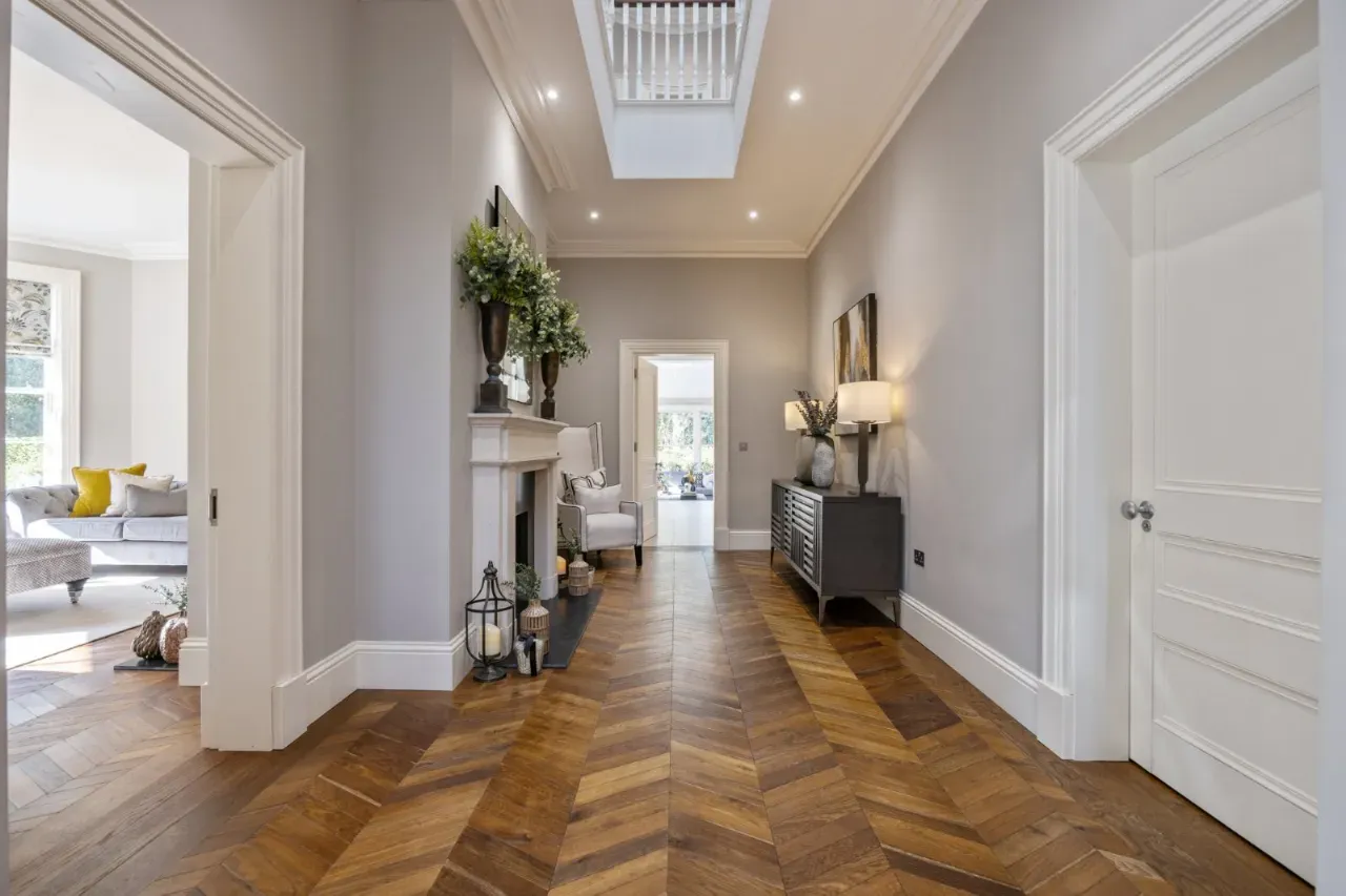 A bright hallway with herringbone oak flooring in a marketed home.