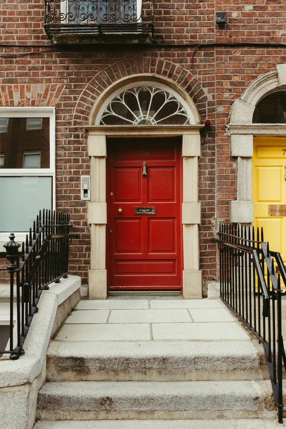 A red Georgian doorway with a stone surround and iron railings.