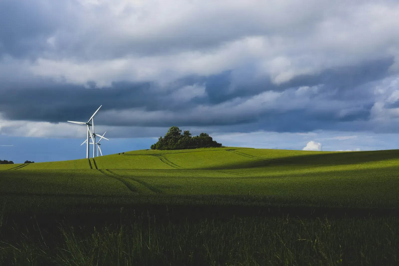 Wind turbines above green fields beneath a clouded sky in Denmark.